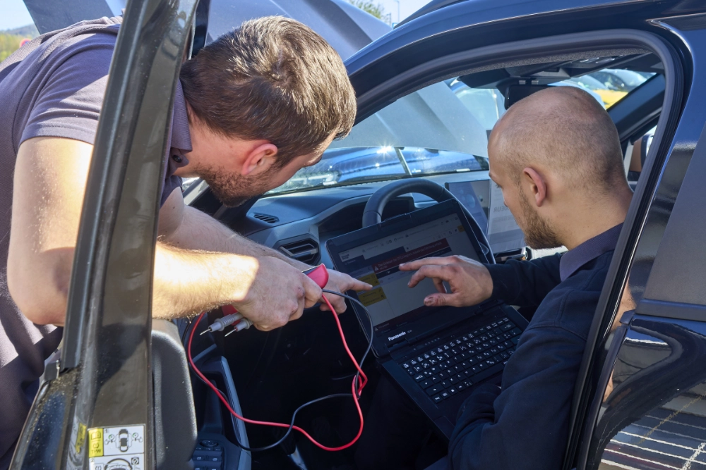 Foto zeigt 2 Mitarbeiter im Teamgespräch bei der Analyse in der Werkstatt